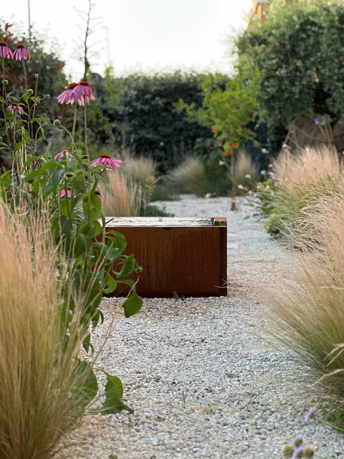 Vialetto in ghiaia con graminacee e fontana in corten, giardino Nido AbitoVerde