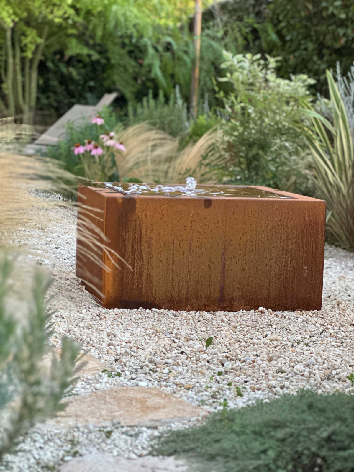 Giardino Nido con echinacea, graminacee e fontana in acciaio corten su ghiaia, AbitoVerde