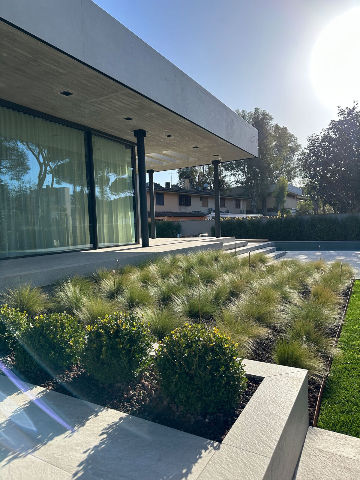 Graminacee ornamentali in file su lapillo con bordo in corten, aiuola contemporanea AbitoVerde