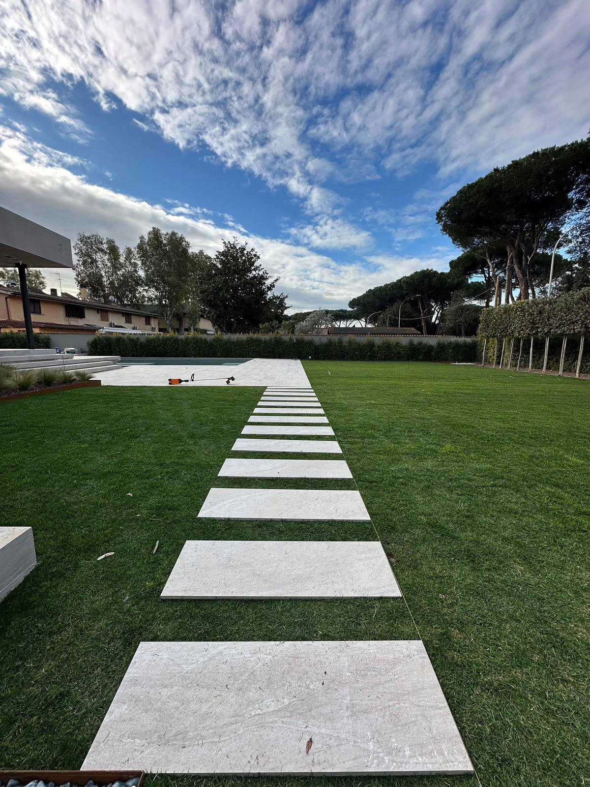 Camminamento in lastre su prato verso area living esterna, progetto giardino contemporaneo AbitoVerde
